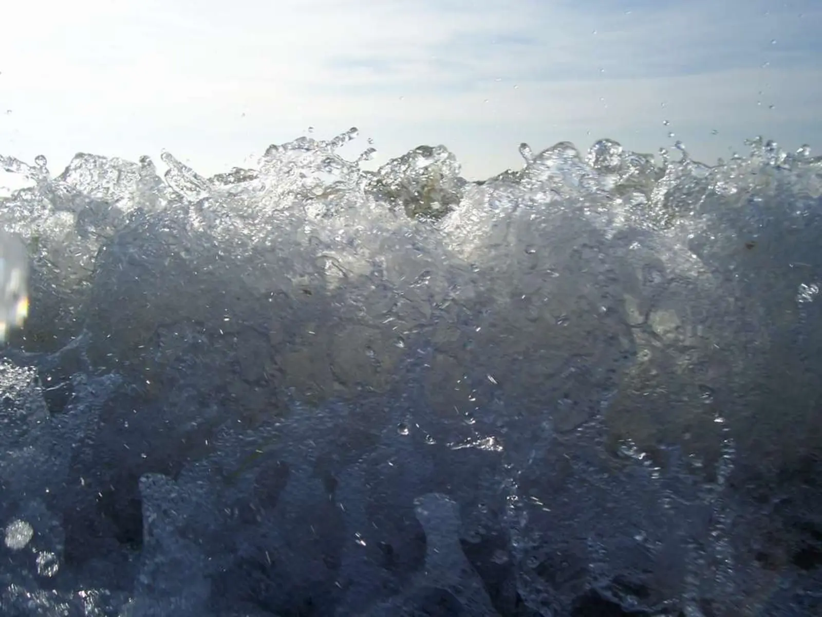 A close-up view of a splashing wave in the sea, with water droplets suspended in the air against a bright sky. The photographer titled it “Baltic Sea Wave (Cien Water)”.