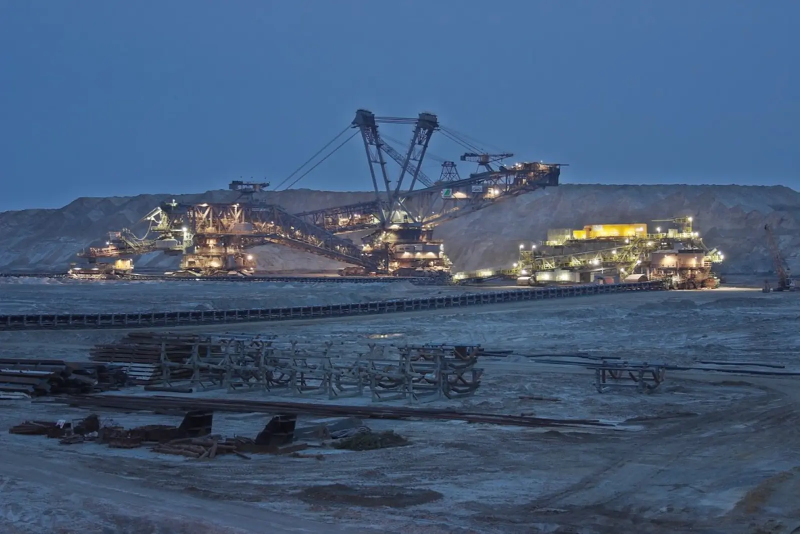 Several large, illuminated open-pit mining excavators and conveyor structures are visible at twilight. The photographer titled it “Excavator - Open Pit Mining”.